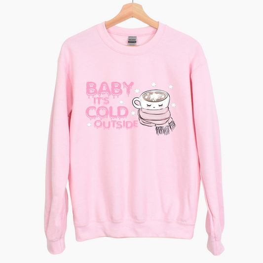 pink fleece crewneck sweatshirt with pink melting letters saying BABY IT'S COLD OUTSIDE and a hot coco mug with marshmallow surrounded by a pink scarf wrapped around the mug