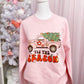 pink fleece crew neck sweatshirt with printed design saying 'TIS THE SEASON , including a pink truck carrying a Christmas tree